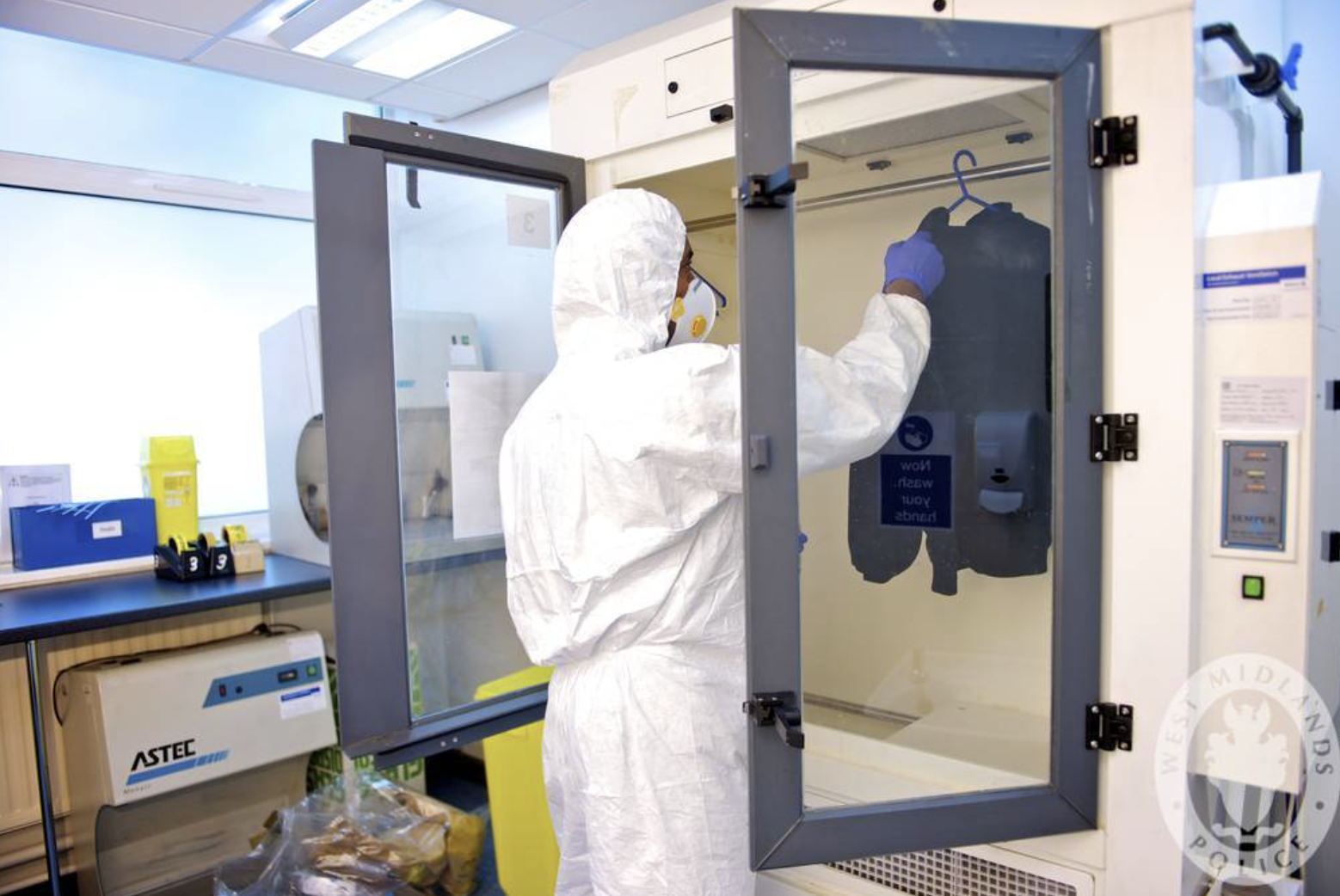 Investigador forense utilizando un gabinete especializado para secar prendas húmedas